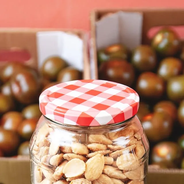Tarro de almendras marconas delante de cajas de tomate de la huerta
